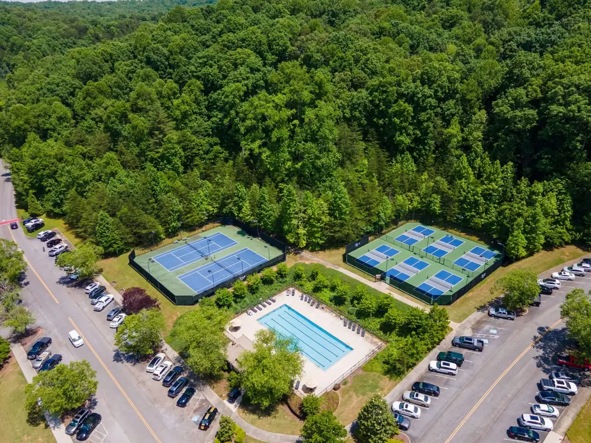 Top-down aerial view of the Achasta swimming pool with two hard tennis courts and six pickleball courts in two rows
