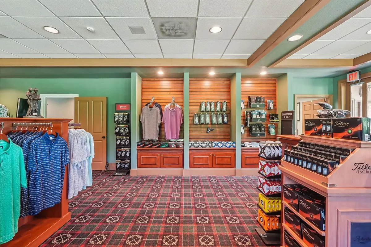 Interior of the Achasta pro shop showing apparel racks, Titleist golf-ball display, and a mannequin in men's golf attire