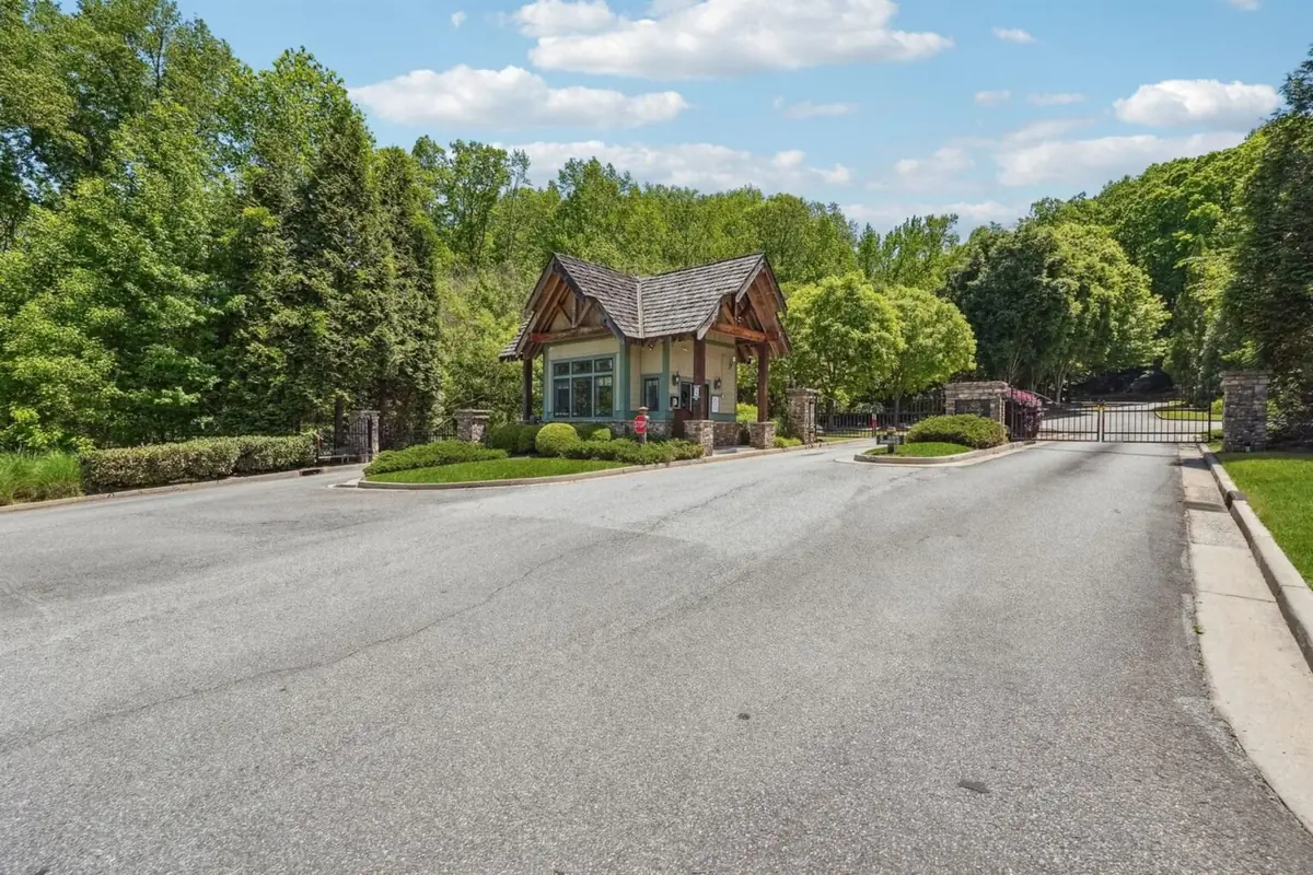 Achasta secondary gate — stone and timber gatehouse with shake roof and a closed wrought iron driveway gate