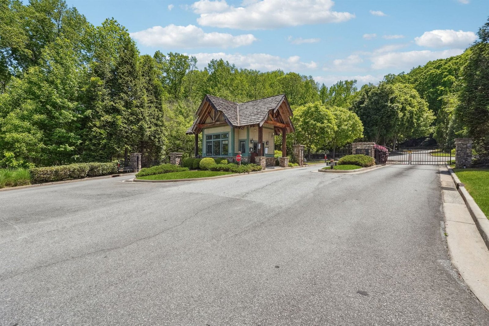 Achasta secondary gate &mdash; stone and timber gatehouse with shake roof and a closed wrought iron driveway gate